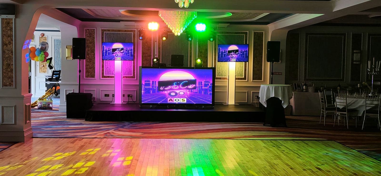 DJ booth, uplighting and dancefloor set up for an 80s night